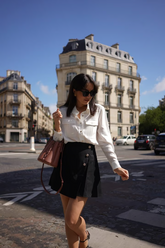 a lady wears an acetate long-sleeve white shirt with a black mini skirt